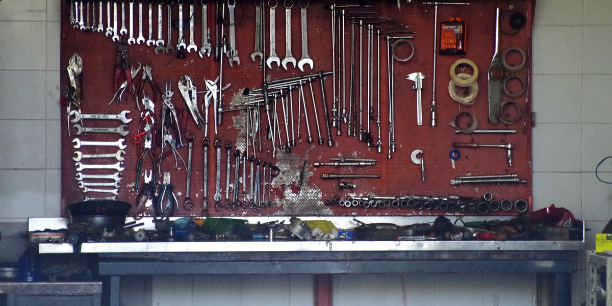 Painel de ferramentas pendurado na parede sobre uma bancada de oficina